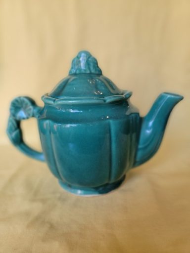 Teal ceramic teapot with a decorative lid and spout.