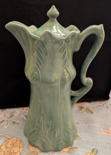 Elegant green pitcher with intricate floral design and a decorative spout.
